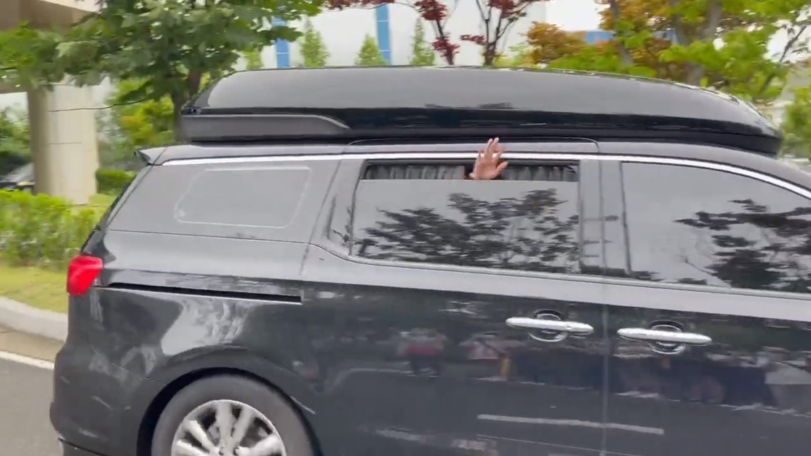 V BTS membuka kaca jendela mobil untuk menyapa penggemar dan awak media