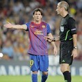 Lionel Messi dari Barcelona berargumen dengan wasit di sela-sela pertandingan melawan AC Milan