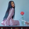 Min Hyo Rin cantik duduk di atas meja ditemani setangkai bunga